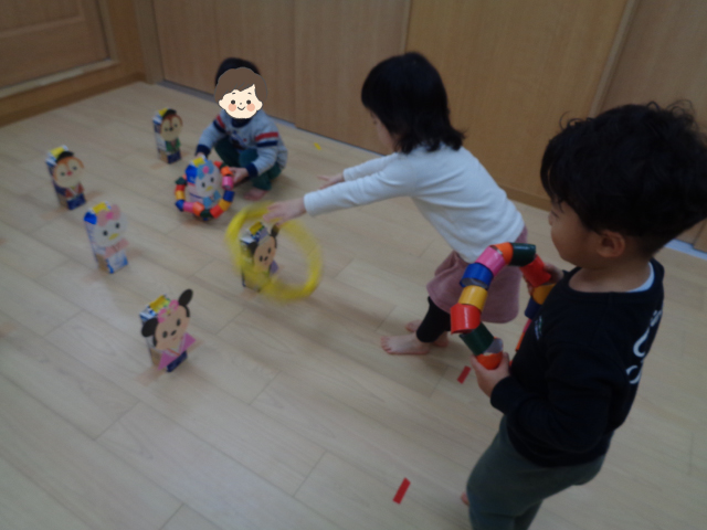 手作りひな人形の輪投げで遊ぶ園児たち